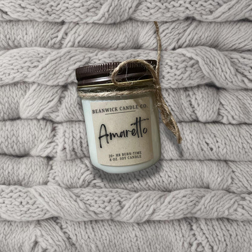 a jar of candle sitting on top of a pile of blankets