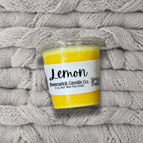 a jar of lemon scented candle sitting on top of a pile of blankets