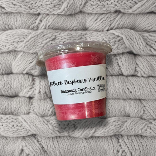 a cup of red candles sitting on top of a pile of blankets