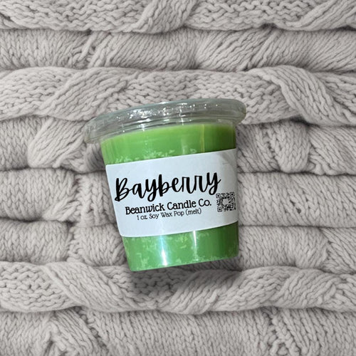 a jar of green candles sitting on top of a pile of blankets