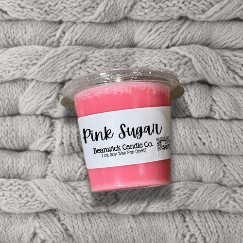 a pink candle sitting on top of a pile of blankets