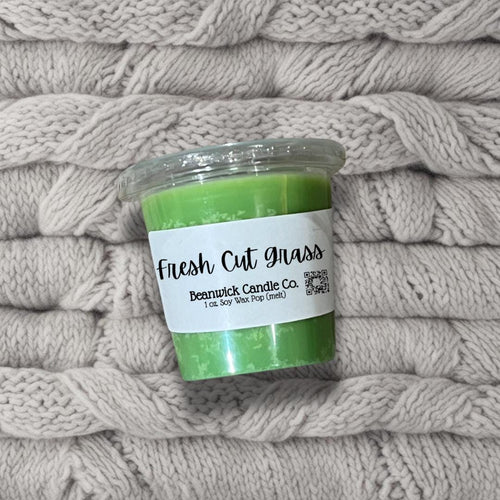 a jar of fresh cut grass sitting on top of a pile of blankets