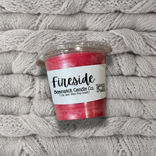 a cup of pink candles sitting on top of a pile of blankets