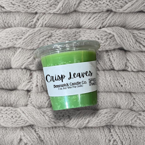 a green candle sitting on top of a pile of blankets