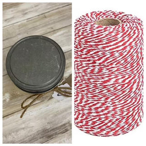 a spool of red and white bakers twine next to a spool