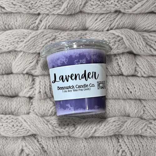 a purple candle sitting on top of a pile of blankets