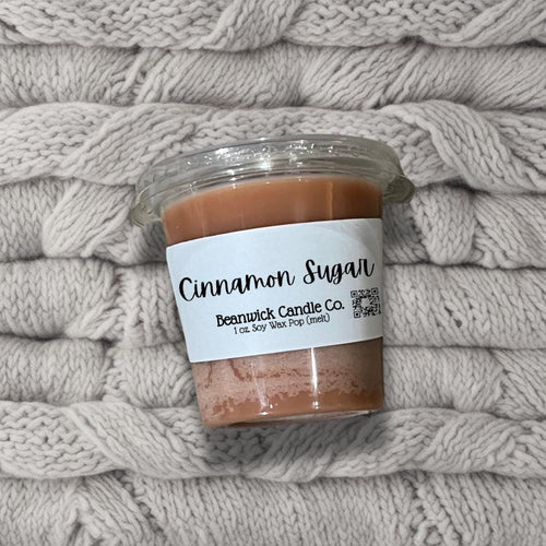 a jar of cinnamon sugar sitting on top of a pile of blankets