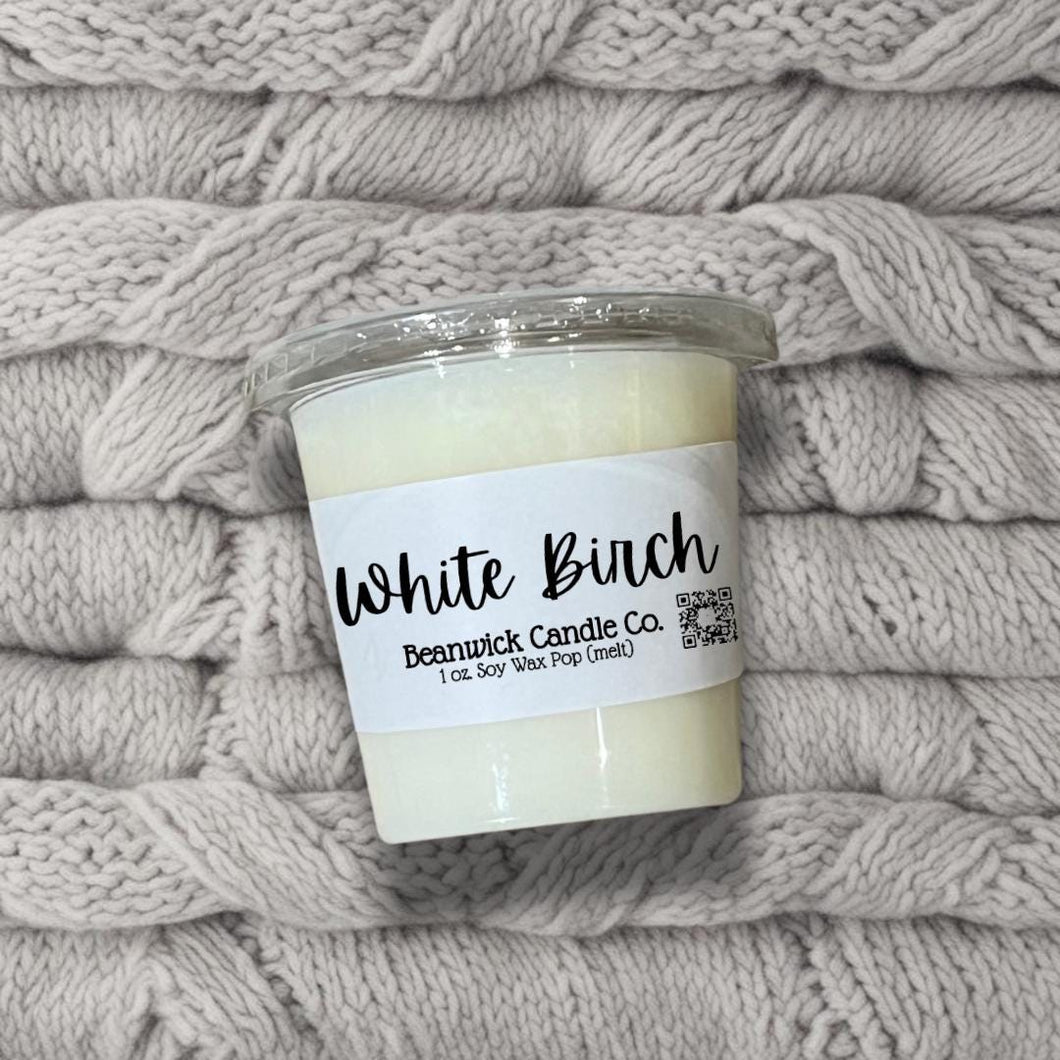 a white candle sitting on top of a pile of blankets
