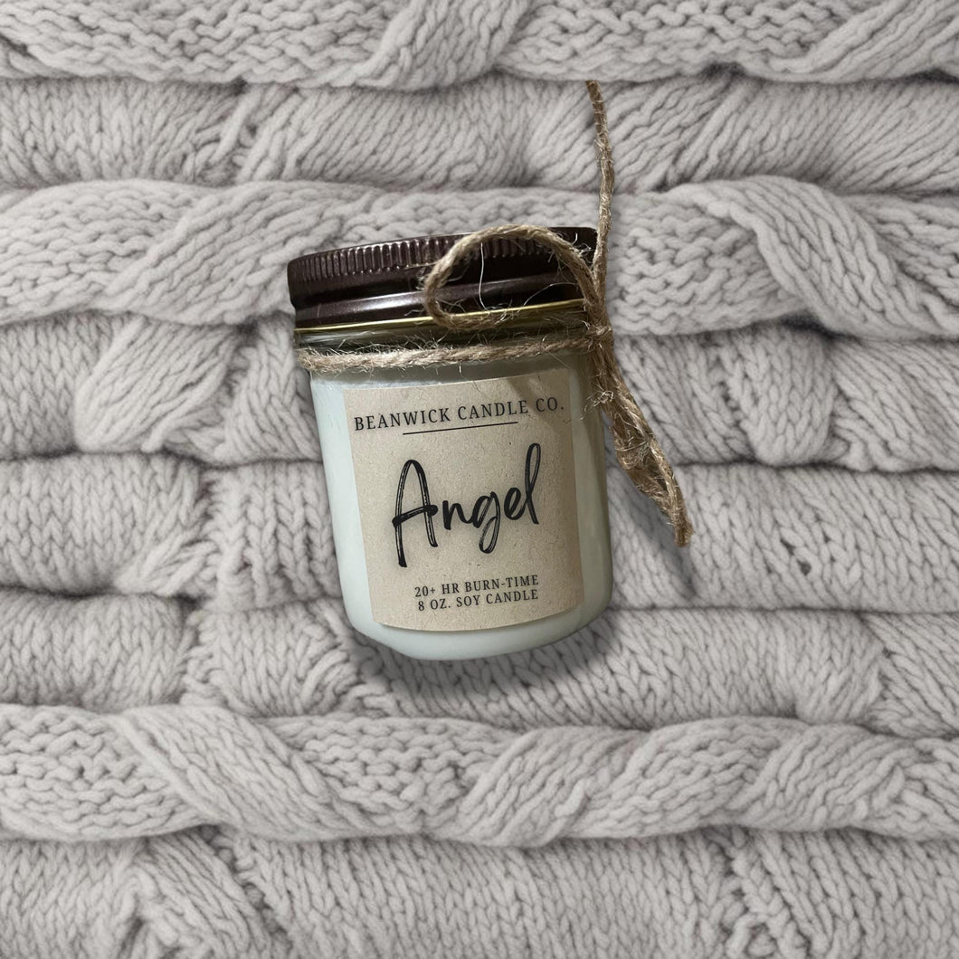 a jar of angel candle sitting on top of a pile of blankets