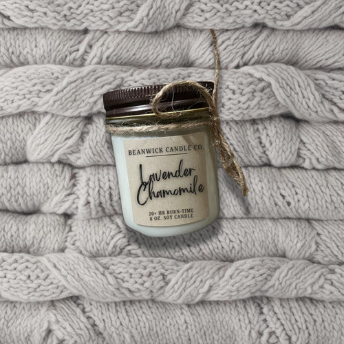 a jar of candle sitting on top of a pile of blankets