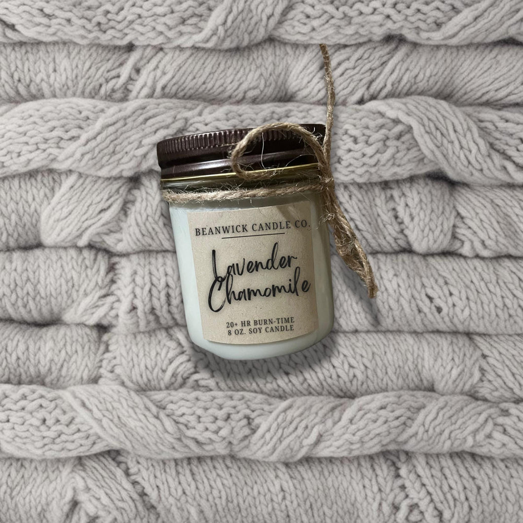 a jar of candle sitting on top of a pile of blankets