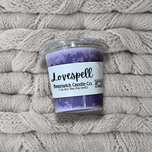 a purple candle sitting on top of a pile of blankets