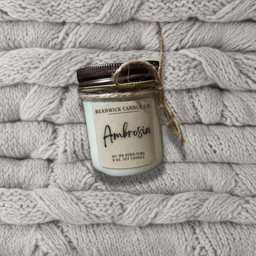 a jar of candle sitting on top of a pile of blankets