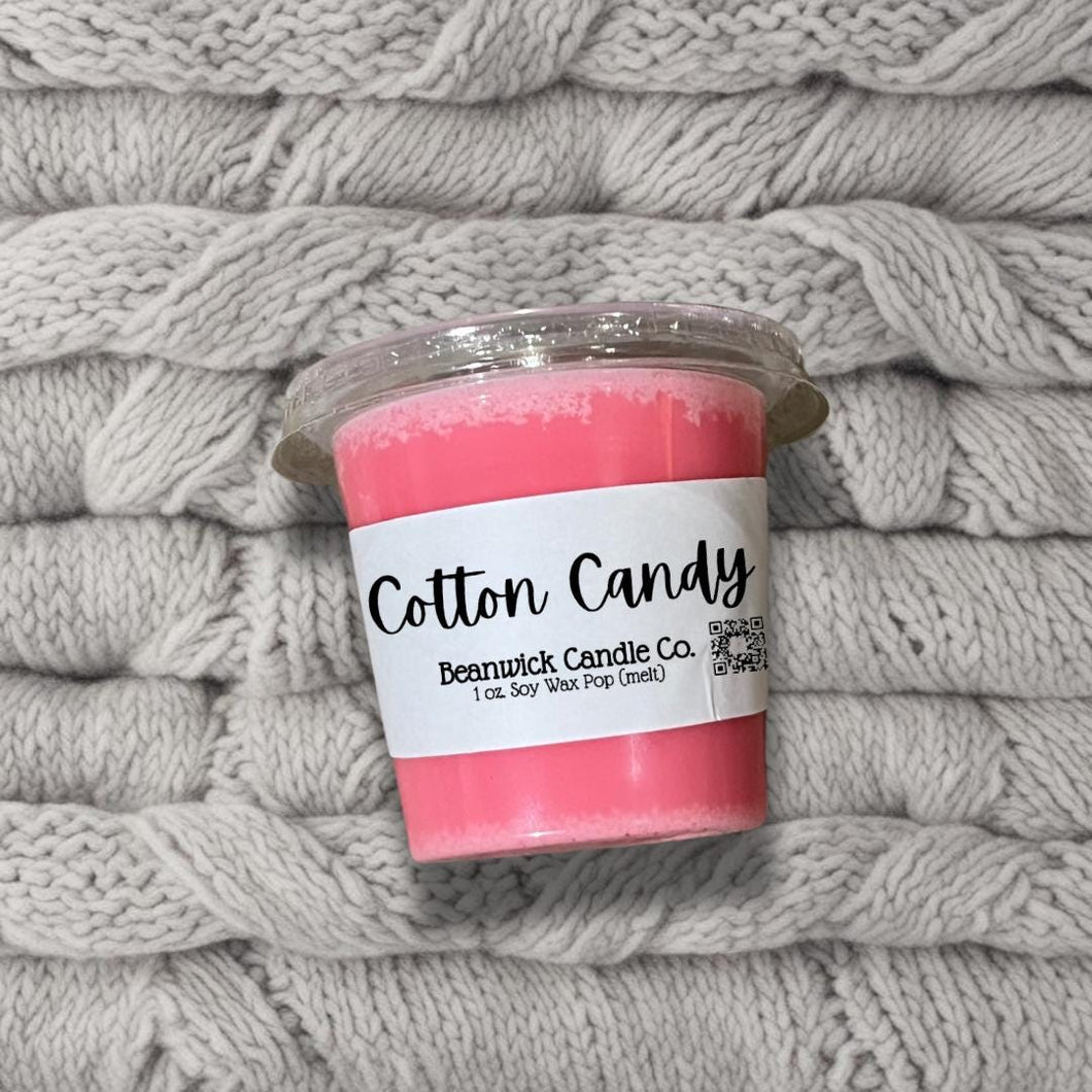 a cup of cotton candy sitting on top of a pile of blankets
