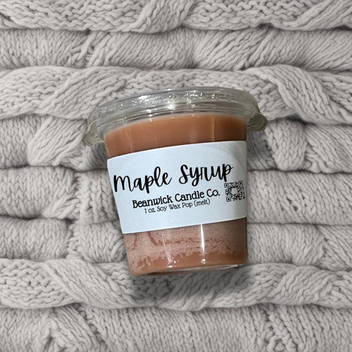 a jar of maple syrup sitting on top of a pile of blankets
