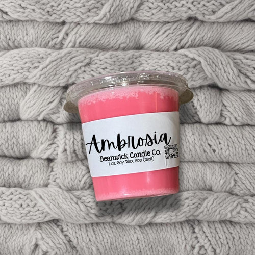 a pink candle sitting on top of a pile of blankets