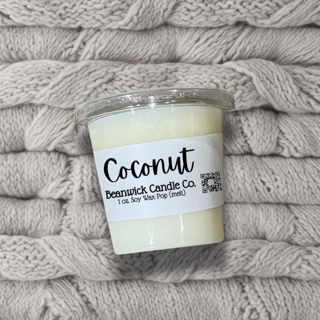 a jar of coconut candle sitting on top of a pile of blankets