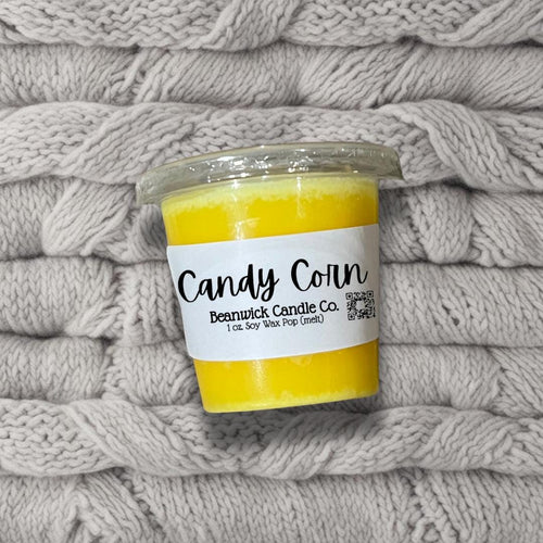 a jar of candy corn sits on a pile of blankets