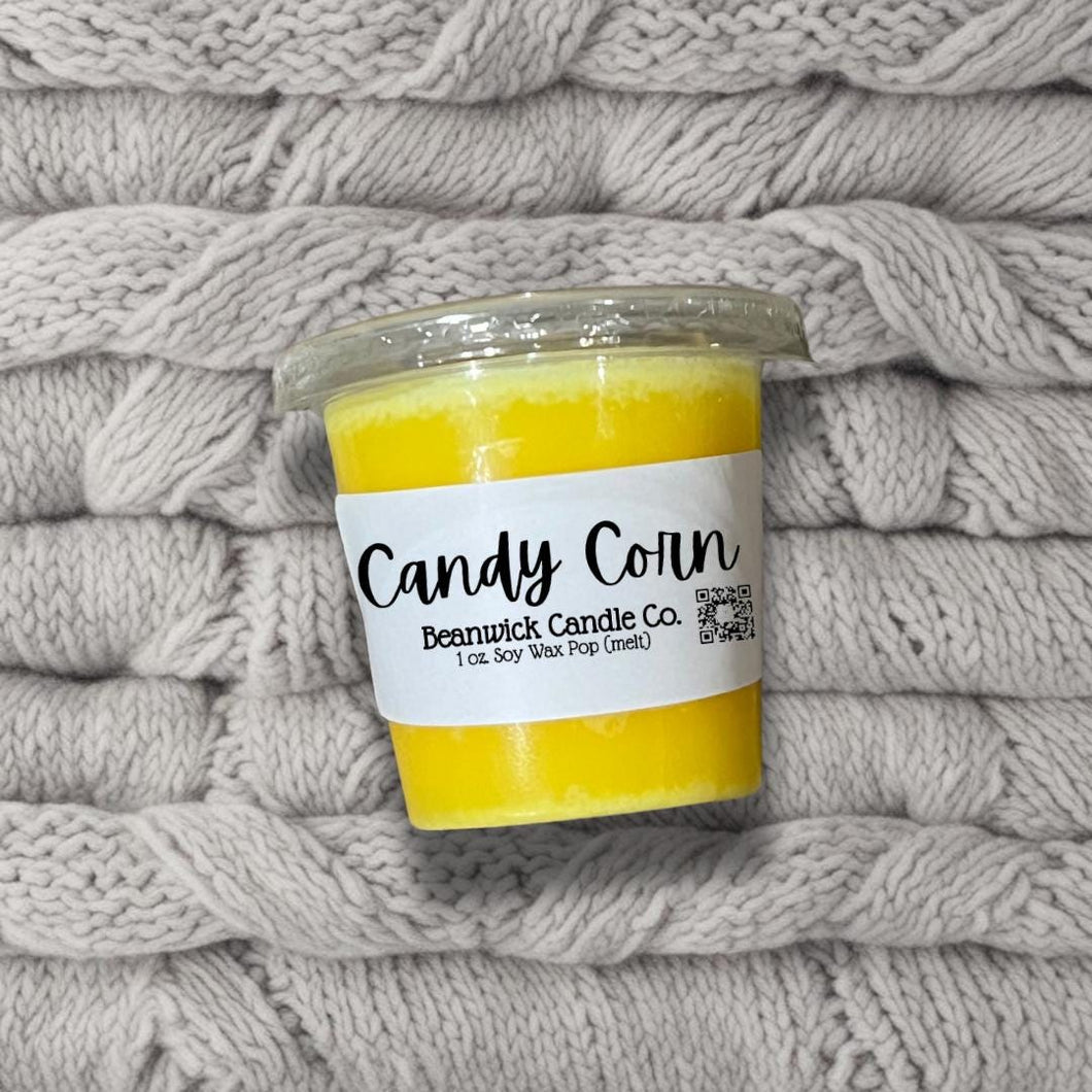 a jar of candy corn sits on a pile of blankets