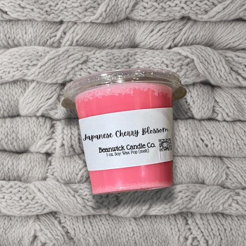 a pink candle sitting on top of a pile of blankets