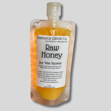 Load image into Gallery viewer, a bottle of raw honey on a gray background